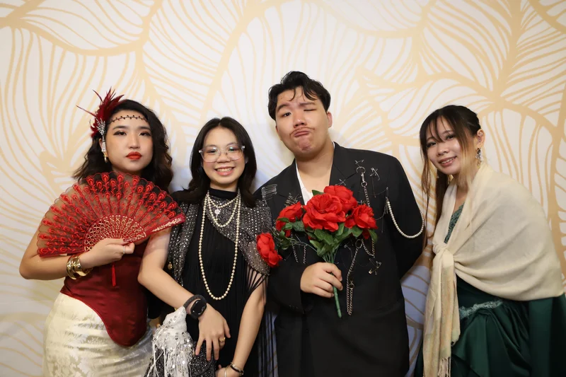 Guests in Gatsby-themed 1920s outfits posing at a Dinner and Dance photo booth in Singapore