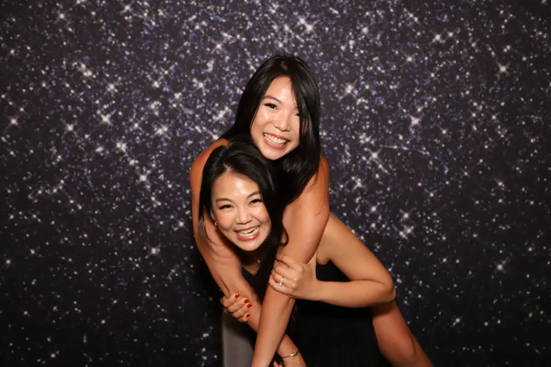 Two friends laughing against a starry glitter backdrop at a Singapore photo booth